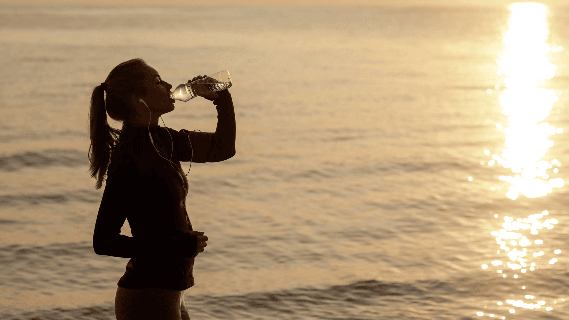 Young Sporty Woman Drinking Water on the Beach